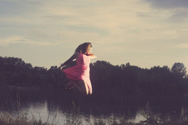 Young Tattooed Woman Jumping over the Lake on a Summer Day - Photo, Image