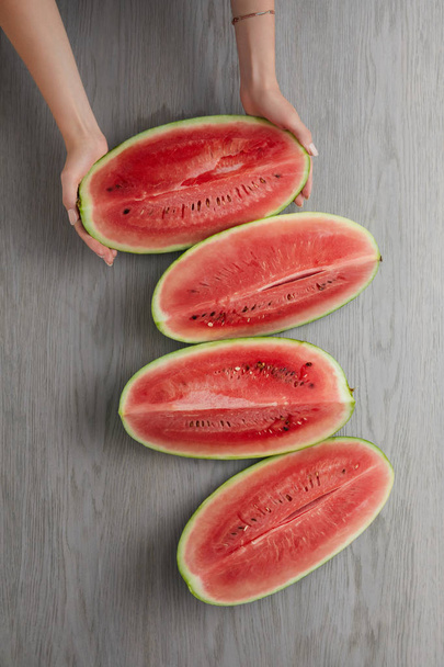 cropped shot of female hands and fresh watermelon slices on grey wooden surface - Foto, imagen