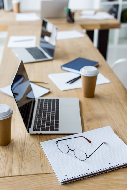 laptops com copos de café descartáveis na mesa no escritório de negócios
 - Foto, Imagem