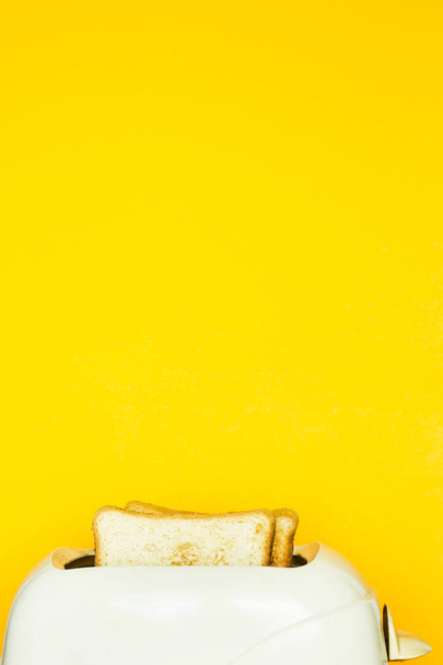 Geroosterd brood stokken uit de broodrooster op een gele achtergrond. Pop-Art. Kopiëren van ruimte - Foto, afbeelding