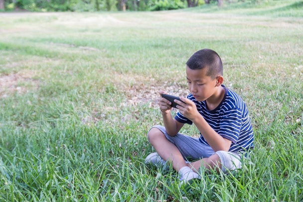 Jovem bonito asiático menino usando um smartphone para jogar jogo sem cuidado o circundante
. - Foto, Imagem