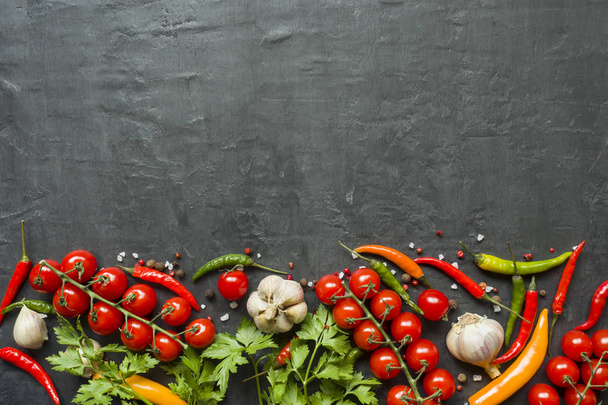 Chili cherry tomaten knoflook en andere kruiden op zwarte achtergrond. - Foto, afbeelding