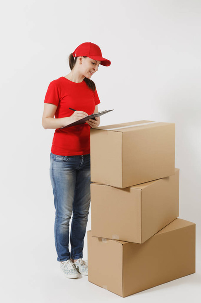Frau in roter Mütze, T-Shirt auf weißem Hintergrund. Kurierin hält Klemmbrett mit Papieren in der Hand, leeres Blatt auf leeren Kartons. Empfangspaket - Foto, Bild
