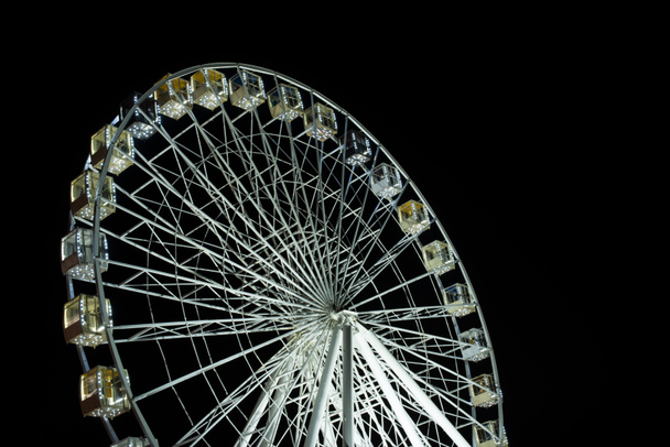 селективное фокусирование освещенного колеса наблюдения ночью на черном фоне
 - Фото, изображение