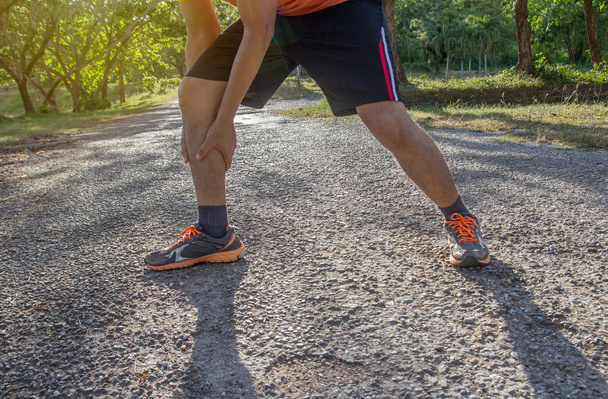L'uomo asiatico usa le mani tenere sulla caviglia durante la corsa su strada nel parco. sport e concetto di allenamento
 - Foto, immagini