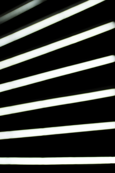 close up view of blurred white lightning lamps on black background - Fotografie, Obrázek
