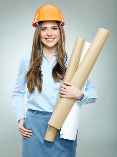 Woman architect wearing builder helmet holding paper plans - Photo, Image