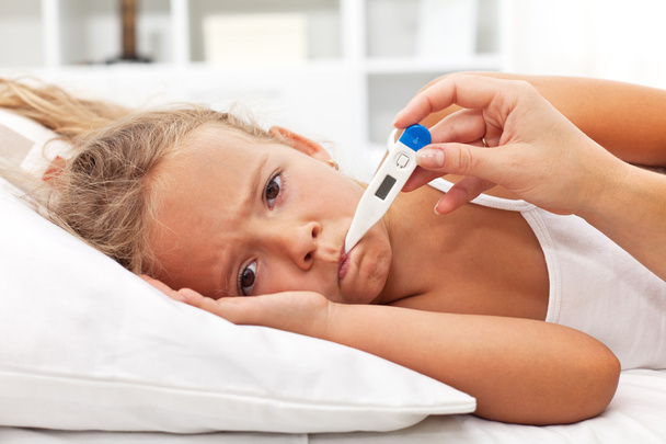 Sick little girl with thermometer laying in bed - Foto, immagini