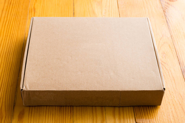 Craft unlabeled cardboard box with copyspace for text on wooden  - Fotoğraf, Görsel