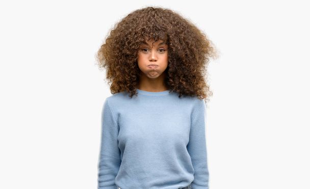 Mujer afroamericana usando un suéter hinchando mejillas con cara graciosa. Boca hinchada con aire, expresión loca
. - Foto, Imagen