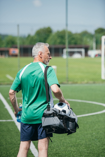 widok na stary człowiek z sportive butelkę wody i torba z powrotem na boisko do piłki nożnej - Zdjęcie, obraz