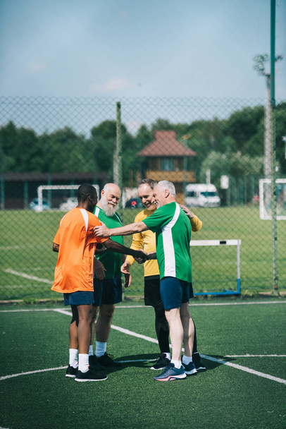 interracial elderly football players after match on green field - 写真・画像