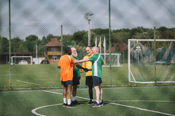 interracial elderly football players after match on green field - Zdjęcie, obraz