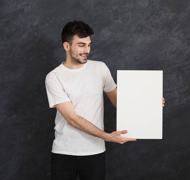 Young cheerful man with blank white paper - Fotoğraf, Görsel