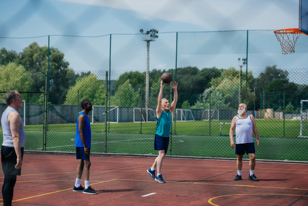 межрасовые пожилые спортсмены вместе играют в баскетбол на детской площадке
 - Фото, изображение