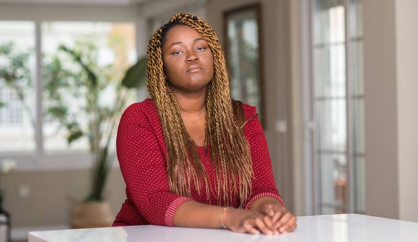 Femme afro-américaine assise à la maison avec une expression confiante sur la pensée intelligente visage grave
 - Photo, image