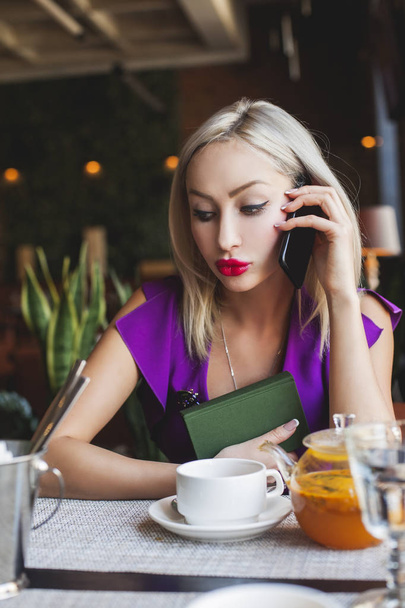 Mujer rubia con teléfono celular en la cafetería
 - Foto, imagen