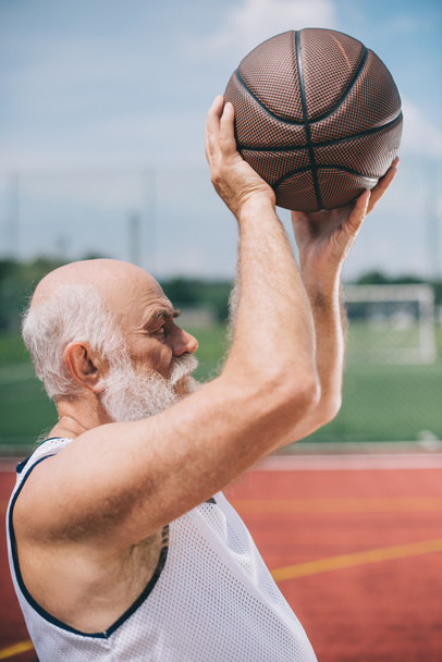 side view of elderly bearded man with basketball ball in hands - Fotó, kép