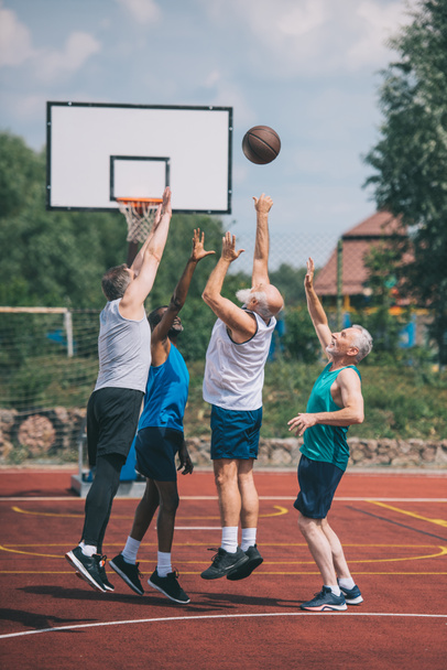 interracial ancianos deportistas jugando baloncesto juntos en patio de recreo
 - Foto, imagen
