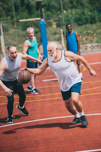 interracia idosos desportistas jogar basquete juntos no parque infantil
 - Foto, Imagem