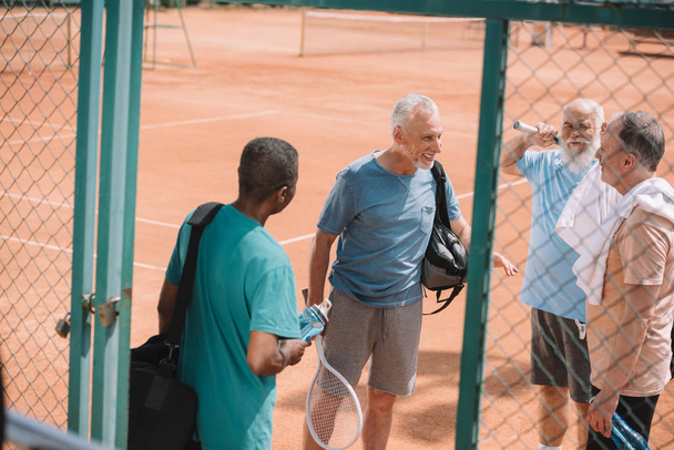 multiracial group of elderly friends with tennis equipment on court - Fotó, kép