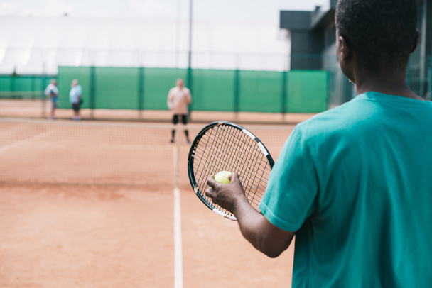 selective focus of elderly african american man playing tennis with friend on court - Valokuva, kuva