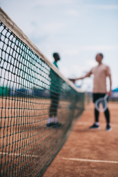 selective focus of friends shaking hands after playing tennis on court - Photo, Image