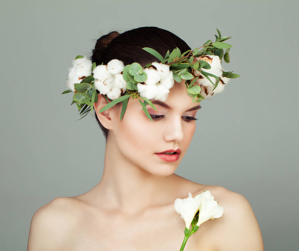 Mujer joven modelo spa con piel clara, flores de algodón y hojas verdes. Concepto de cuidado de la piel
 - Foto, imagen