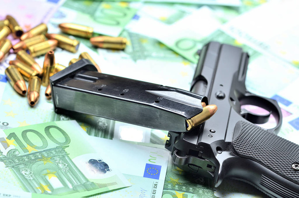 Pistole, geladenes Magazin und Kugeln auf Euro-Banknoten - Foto, Bild
