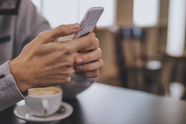 руки з мобільним телефоном і чашкою кави в кафетерії
 - Фото, зображення