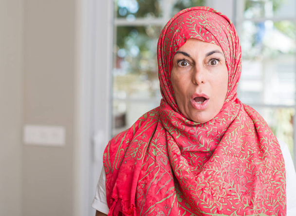 Mujer musulmana de mediana edad usando hijab asustada en shock con una cara sorpresa, asustada y excitada con expresión de miedo
 - Foto, imagen