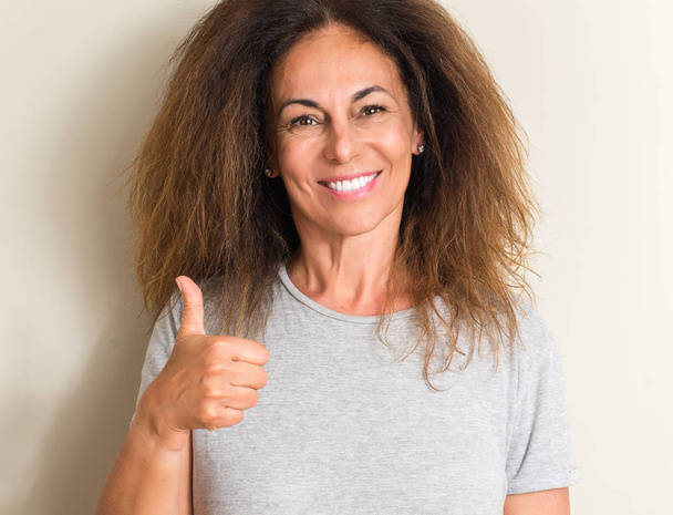 Κατσαρά μαλλιά Βραζιλίας γυναίκα ευτυχισμένη με μεγάλο χαμόγελο κάνει εντάξει σήμα, τον αντίχειρα επάνω με τα δάχτυλα, καλό σημάδι - Φωτογραφία, εικόνα