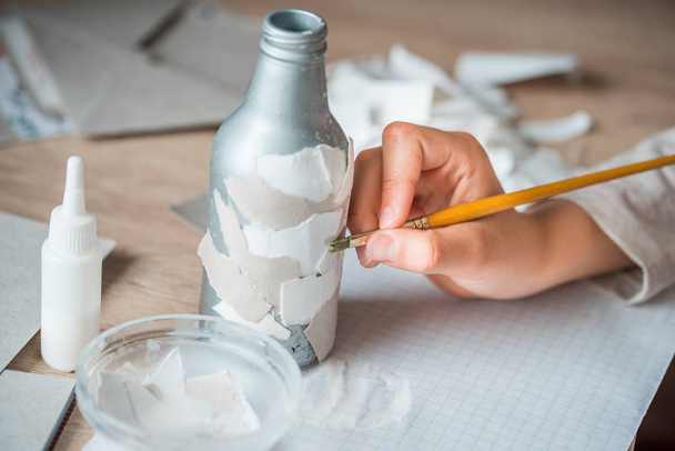 secondary use of paper debris. children's handmade from papier mache. The baby's hands are glued to pieces of paper on the bottle - Foto, Bild
