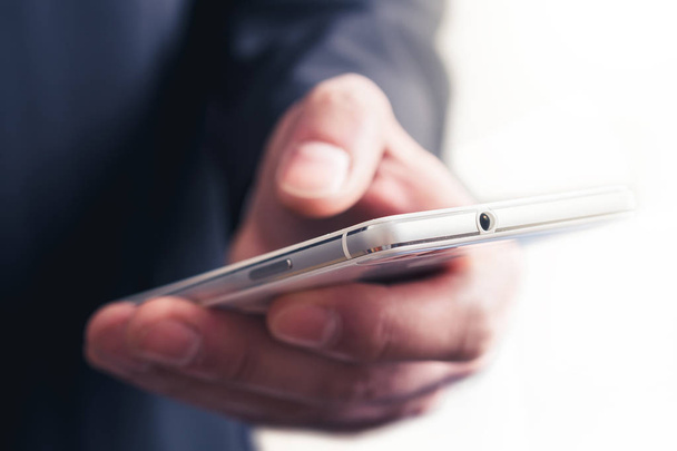 Close Up de um empresário tocando um telefone celular na frente de um fundo brilhante
 - Foto, Imagem