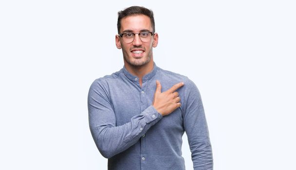 Handsome young elegant man wearing glasses cheerful with a smile of face pointing with hand and finger up to the side with happy and natural expression on face looking at the camera. - Photo, Image
