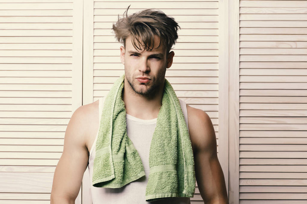 Man with green towel around neck. Athlete with strong muscles after morning shower. Exercising and healthy lifestyle concept. Guy with messy hair and sexy face expression - Valokuva, kuva