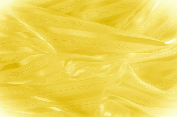 Háttér textúra, minta. Sárga selyem anyag-egy világos csíkkal. Sárgás szövet. Sima, elegáns sárga szatén háttér. - Fotó, kép