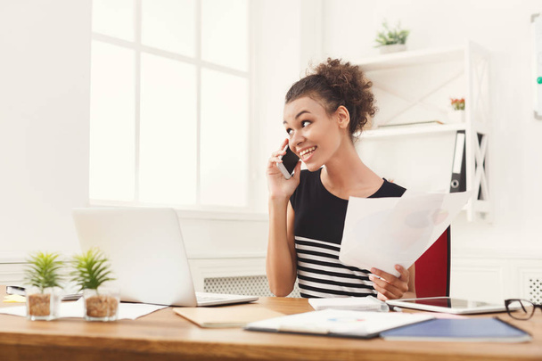 Smiling woman consulting by phone at office - Photo, Image