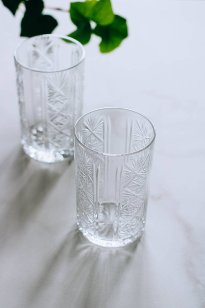 Two empty glasses on a marble background, with a twig of ivy - 写真・画像