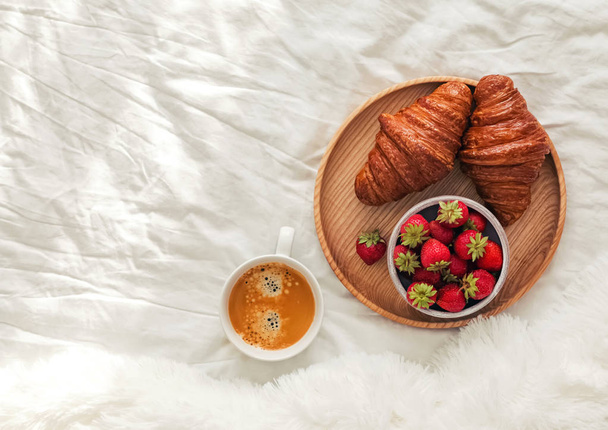 Coffee in croissants on the white bedding in the room full of sunlight. - Photo, Image