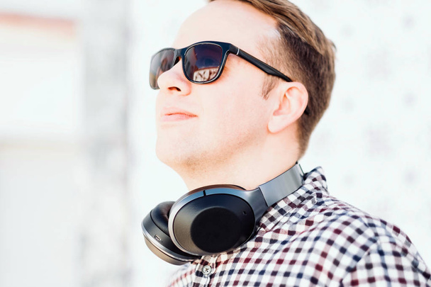 Man with sunglasses and fancy headphones on his neck in the southern city - Foto, Imagen