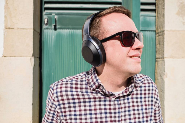 Nuori mies nauttii musiikkia fancy moderni kuulokkeet ulkona
 - Valokuva, kuva