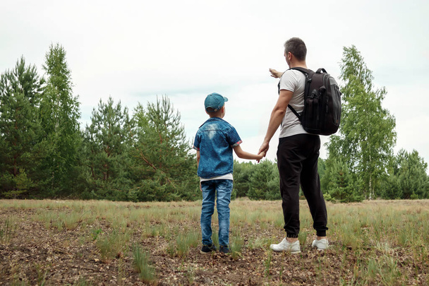 A man with a backpack, a father and his son on a hike, walking during walks in the woods. Family life, pastime with the family, the upbringing of children. - Photo, Image