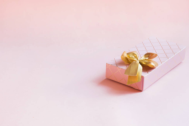 Female gift box with golden ribbon on punchy pastel pink. Birthday. Copy space. - Fotoğraf, Görsel