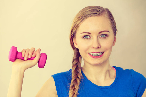 Teenage young woman working out at home with small light dumbbells. Training at home, being fit and healthy. - Photo, image