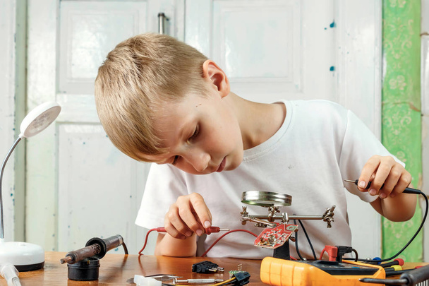 The child remotiruet microcircuit. Workplace with soldering iron, microcircuit, magnifying glass, magnifying glass, measuring instruments. Choice of profession. - Foto, immagini