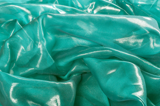 Textura, pozadí, vzor. Hedvábná látka modrá, tenké vzdušné hedvábné tkaniny, textilie odráží sluneční paprsky - Fotografie, Obrázek
