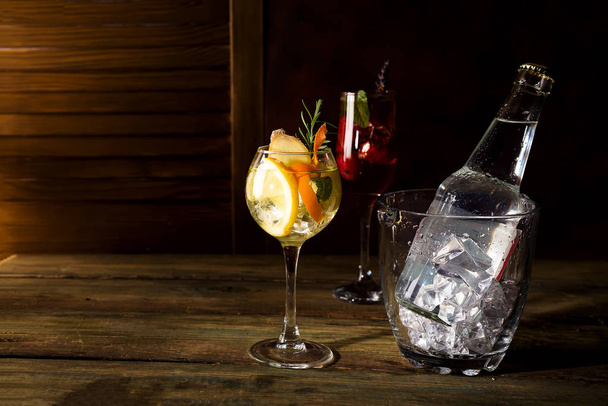 Um cocktail à base de uísque, misturado com balde de gelo de vidro e uma casca de laranja com acessórios Bar em backgorund de madeira escura
 - Foto, Imagem