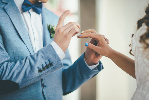 ein stilvoller Bräutigam, der einen Ring am Finger seiner eleganten Brautfliege trägt - Foto, Bild