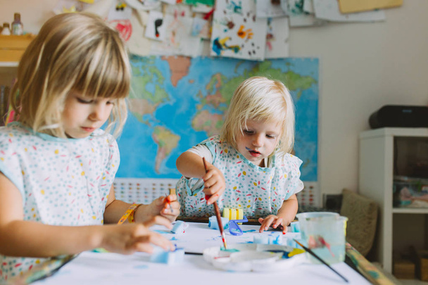 portrait of happy adorable little girls drawing with paints at home, closeup - Foto, Imagem